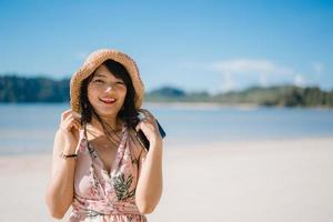 bela jovem asiática feliz relaxe andando na praia perto do mar. mulheres de estilo de vida viajam no conceito de praia. foto