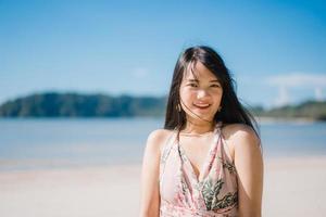 bela jovem asiática feliz relaxe andando na praia perto do mar. mulheres de estilo de vida viajam no conceito de praia. foto