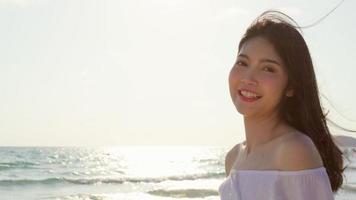 jovem mulher asiática se sentindo feliz na praia, linda fêmea feliz relaxe sorrindo divertido na praia perto do mar ao pôr do sol à noite. mulheres de estilo de vida viajam no conceito de praia. foto