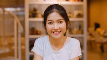 retrato mulher chinesa asiática se sentindo feliz sorrindo na biblioteca da universidade. jovem adolescente de graduação relaxe o sorriso cheio de dentes olhando para a câmera nas horas extras do campus universitário no conceito de noite. foto