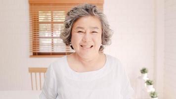 mulher idosa asiática se sentindo feliz sorrindo e olhando para a câmera enquanto relaxa no sofá na sala de estar em casa. mulheres sênior de estilo de vida em casa conceito. foto