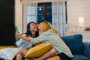 grupo de mulheres asiáticas festa em casa, feminino bebendo cerveja assistindo tv cheer futebol momento engraçado juntos no sofá na sala de estar à noite. fã de futebol adolescente jovem amigo, comemore o conceito de férias. foto