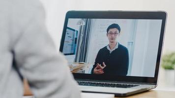 jovem estudante universitário da ásia adolescente usando computador portátil lição de ensino à distância com professor masculino ensino remoto na internet em casa. distanciamento social, quarentena para prevenção do vírus corona. foto