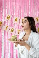 linda mulher animada comemorando aniversário segurando bolo fazendo desejo