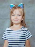 caucasiana adorável menina doce bonitinha com longos cabelos loiros em t-shirt listrada e orelhas de gato foto