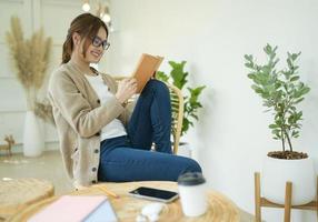 linda garota sentada na sala lendo um livro. foto