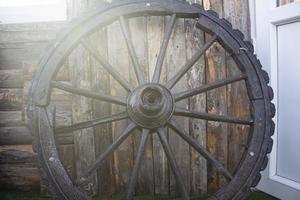 roda de carroça de madeira velha esquecida encostada a uma parede de madeira. estrelinhas na velha parede de madeira da casa. foto