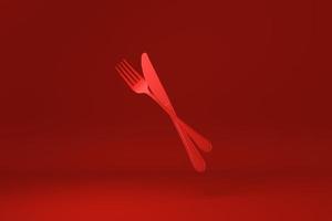 garfo vermelho e faca flutuando em fundo vermelho. ideia de conceito mínimo criativa. monocromático. renderização 3D. foto