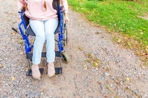 pernas pés deficiente mulher na roda de cadeira de rodas na estrada no parque hospitalar esperando por serviços ao paciente. menina paralisada irreconhecível na cadeira inválida para pessoas com deficiência ao ar livre. conceito de reabilitação. foto