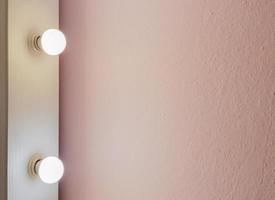 nova parede rosa plana moderna com duas lâmpadas de um grande espelho de chão para maquiagem e compras de corpo inteiro. abstrato moderno fundo de textura na moda. copie o espaço para o seu texto. foto