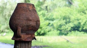 jarro de barro quebrado marrom velho em uma cerca de madeira na zona rural. copie o espaço. pote em uma cerca de aldeia velha foto