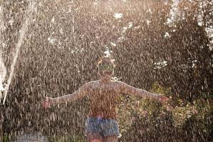 garota feliz atravessa uma fonte em um parque verde ao sol foto