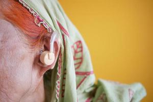 conceito de aparelho auditivo, uma mulher sênior com problemas auditivos. foto