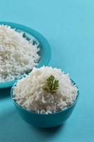 arroz basmati branco puro cozido em um prato azul e uma tigela sobre fundo azul foto