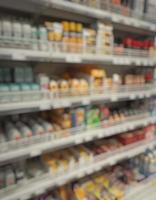 passagem turva de um supermercado com prateleiras com mercadorias. passagem abstrata no supermercado com mercadorias coloridas nas prateleiras, pode ser usada como pano de fundo ou para seu outro projeto foto