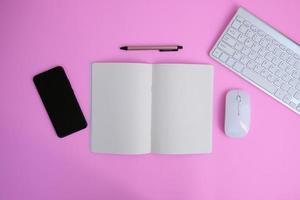 notebook com caneta estão em cima da mesa de escritório com ferramentas e suprimentos de computador. vista superior com espaço de cópia, configuração plana. finanças e publicidade bancária foto