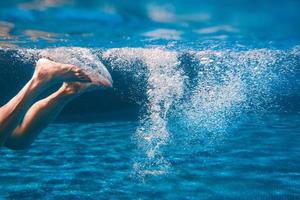 pernas masculinas nadando debaixo d'água na piscina no verão foto