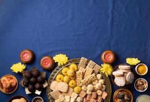 doces indianos tradicionais em fundo azul com velas e flores flat lay foto