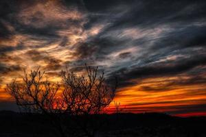 belo pôr do sol de um vermelho ardente com tons de amarelo dourado com nuvens refletindo essas cores esplêndidas do sol foto