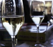 copos de vinho branco em uma mesa posta para um jantar elegante em um restaurante em alba na langhe piemontesa foto