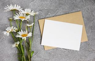 cartão branco em branco e envelope com flores de camomila foto