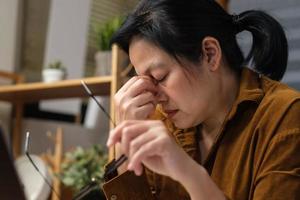 mulher asiática fica estressada enquanto trabalha com laptop em casa foto