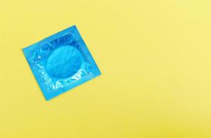 preservativo isolado em fundo amarelo - pacote de preservativo colorido para meios contraceptivos de controle de natalidade prevenir a gravidez ou doenças sexualmente transmissíveis foto