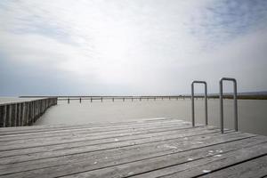 um cais de madeira com escada de alumínio para deck de piscina com corrimão em neusiedlersee na áustria. foto