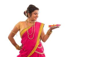 retrato de uma garota tradicional indiana segurando pooja thali com diya durante o festival de luz sobre fundo branco, diwali ou deepavali foto