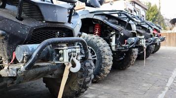 muitos atvs estacionados em uma estrada de terra, de perto. carro de quatro rodas, veículo todo-o-terreno. rodas grandes com pernas poderosas. passeio de montanha nos Cárpatos. foto