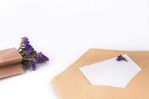 flores azuis, secas em saco de papel pardo e envelope postal no fundo branco... close-up. vista superior, copie o espaço foto