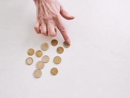 mãos sênior contando moedas de euro em cima da mesa. pobreza, crise, depósito, conceito de recessão foto