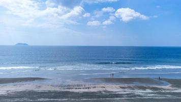 movimento de onda suave e oceano azul no fundo da praia de areia preta. praia de areia preta no parque nacional laem son em ranong, tailândia foto