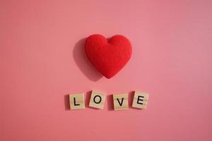 coração vermelho isolado no fundo rosa com amor de palavras de letra. dia dos namorados, presente, mensagem de amante, cartão de felicitações. conceito de amor. foto