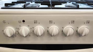 controles do forno a gás. controles em um fogão a gás branco. close-up de interruptores de gás. novos eletrodomésticos para a cozinha. foto