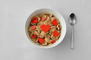 prato com cereal matinal e vista superior de corações vermelhos. café da manhã saudável, conceito. cartão dia dos namorados foto