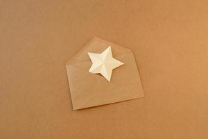 estrela de papel branco em um envelope feito de papel kraft marrom. asterisco no envelope. carta com estrela de papel foto