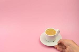 mão de mulher segurando a xícara de café no fundo rosa, vista superior, copie o espaço. estilo minimalista de banner de café foto
