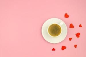 xícara de café e corações de amor vermelho sobre fundo rosa, postura plana. café e dia dos namorados, copie o espaço foto