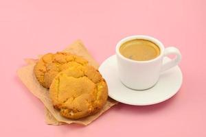 xícara de café preto e biscoitos caseiros em um fundo rosa, café e sobremesa foto