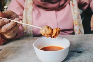 mulheres vestindo véus cor de rosa comem almôndegas de churrasco satay. foto