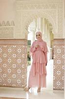 retrato de corpo inteiro de senhora usa um vestido de noiva, maquiagem de casamento no hijab. vestido de noiva malaio ou indonésia, beleza ou conceito eidul fitri. bela mulher muçulmana do sudeste asiático posando na mesquita foto