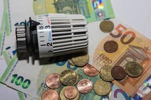 aumento dos preços da energia e regulador termostático do consumo de energia do aquecimento com diferentes notas e moedas de euro macro foto