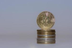 pilha de moeda criptográfica de bitcoins valiosos de ouro com frente de fundo cinza foto