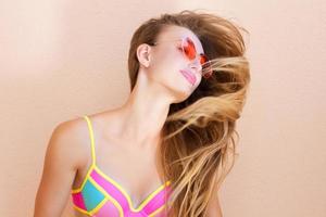 close-up de menina feliz em óculos de sol rosa isolados. férias de verão e fim de semana divertido. conceito de verão. jovem sorridente em maiô de moda. foco seletivo. estilo de roupa de verão de praia. foto