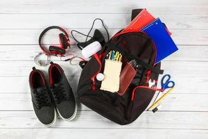 material de mochila escolar e um tablet com fones de ouvido. foto