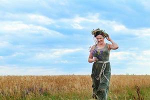 linda garota em um campo de trigo com coroa na cabeça foto