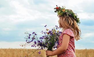 menina com uma coroa de flores sua cabeça campo de trigo foto
