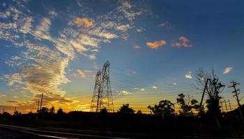 postes de energia de alta tensão no crepúsculo da cena do pôr do sol foto