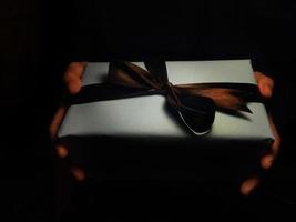caixa de presente na mão de uma mulher em fundo escuro, para aniversário, aniversário e dia de comemoração. ano Novo foto
